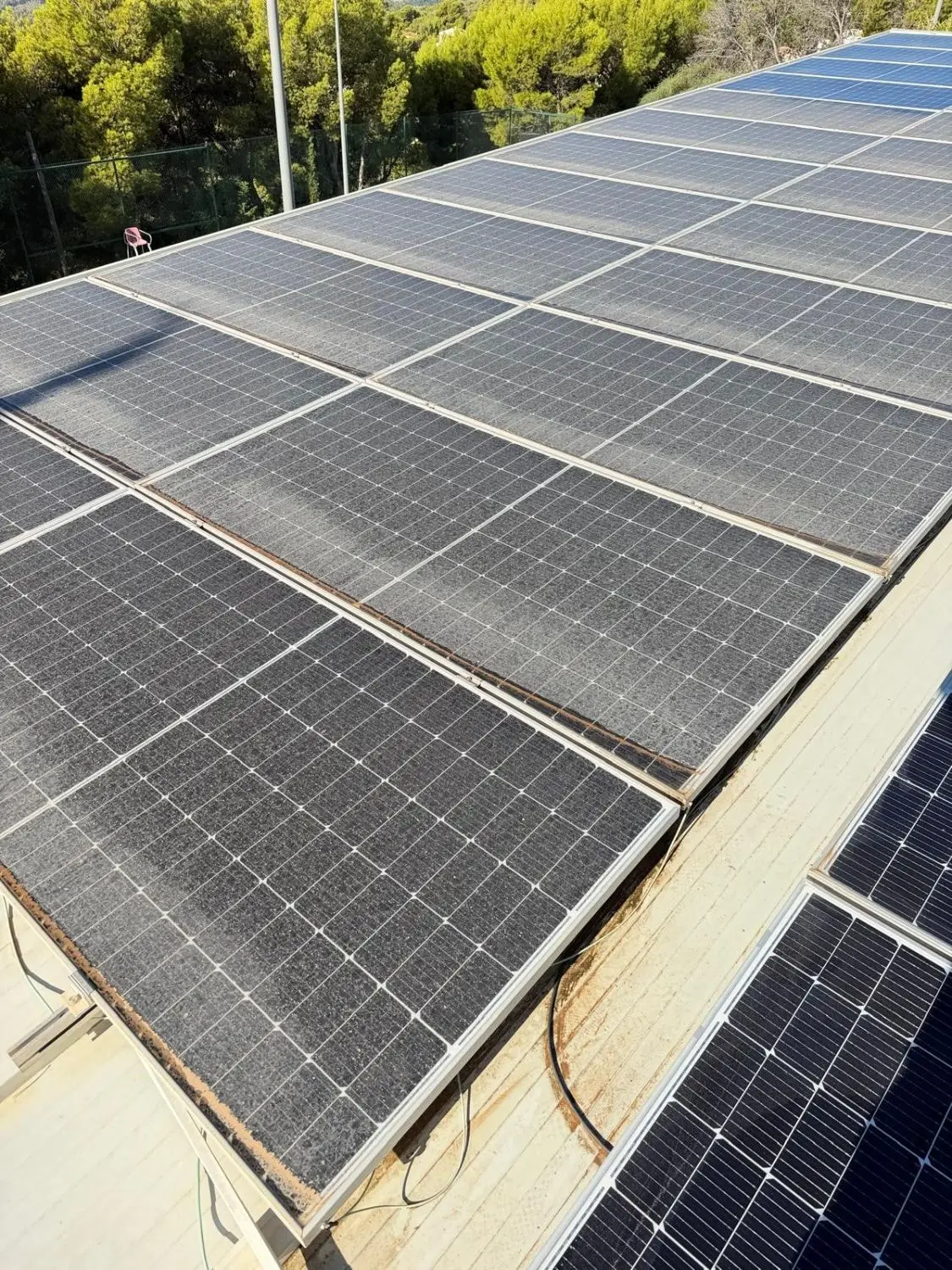 Placas solares cubiertas de polvo, con barro acumulado en el borde inferior